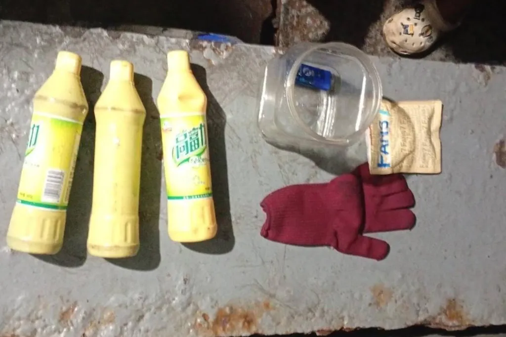 Three yellow bottles of suspected cyanide, a red glove, and a small plastic container on a dirty surface.