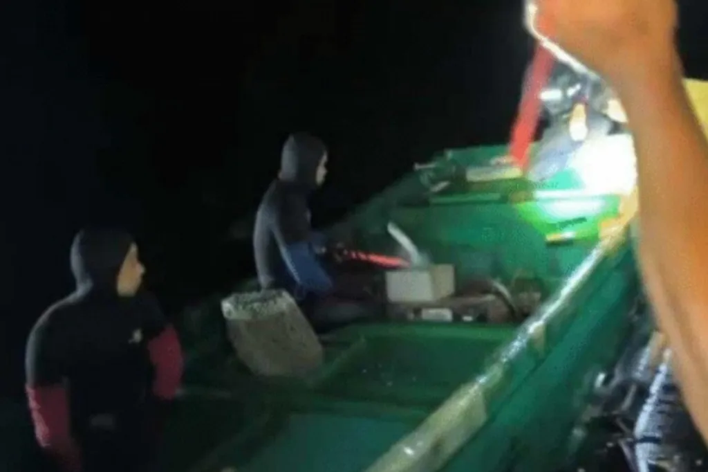 People on a small boat at night using a bright light.