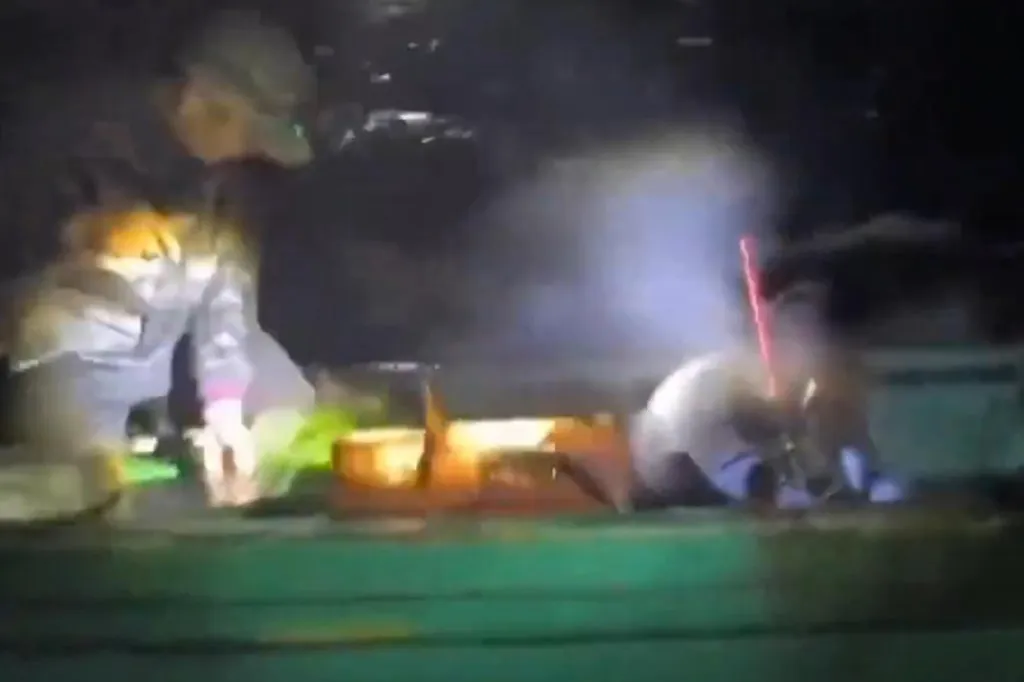 Two Chinese fishermen suspected of using cyanide, with one aiming a laser-like device, on their boat at night.