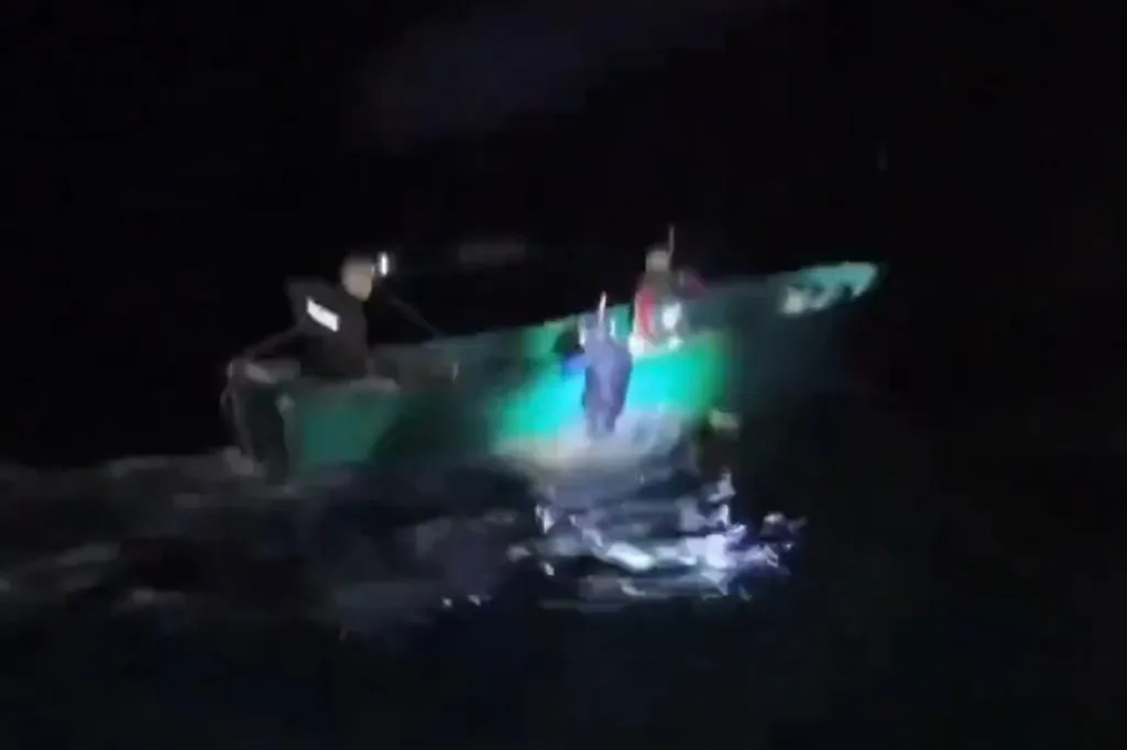 A boat at night with people on board, illuminated by a bright light.