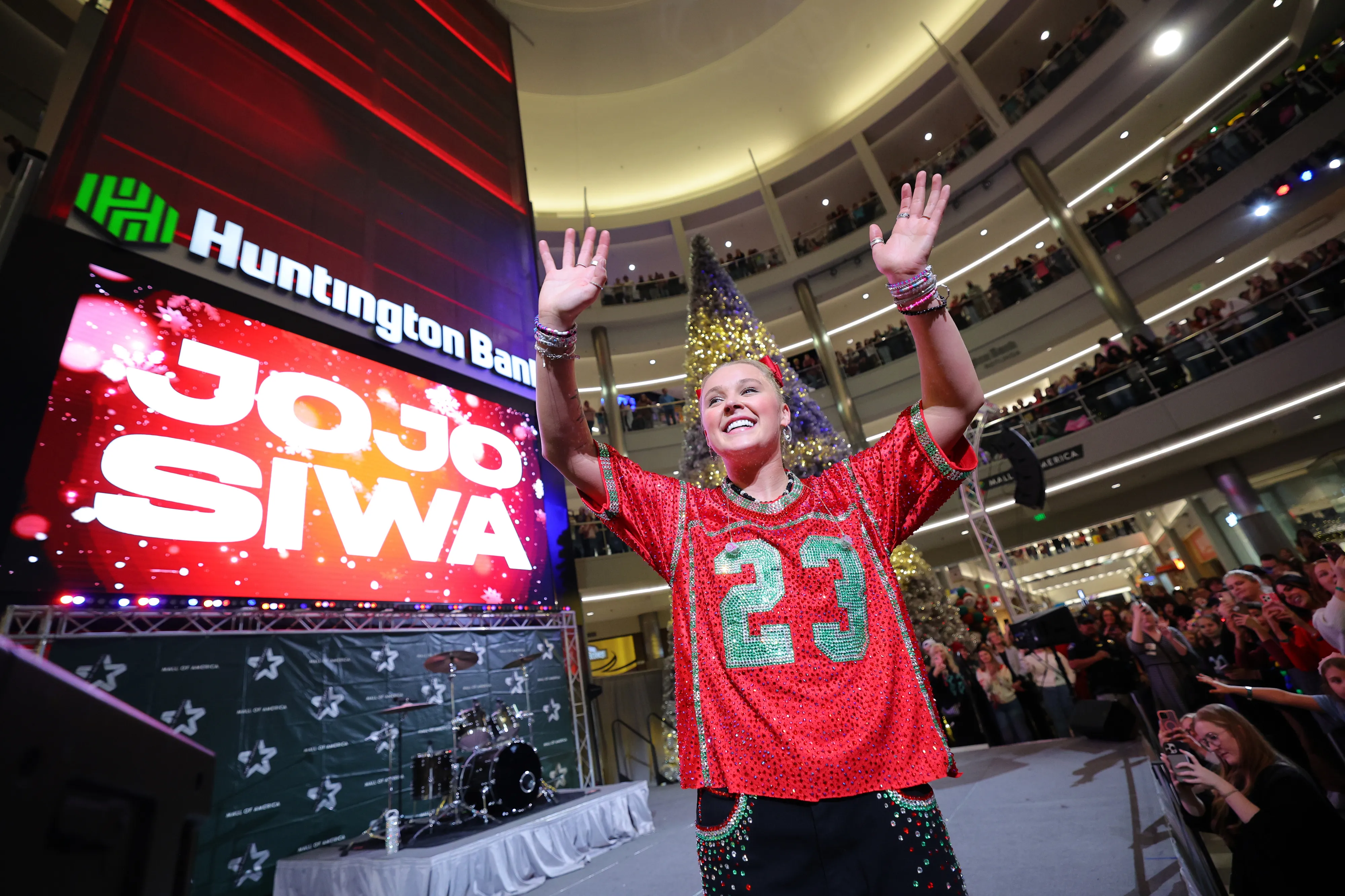 JoJo Siwa performs on stage wearing a red sequined top with a large 