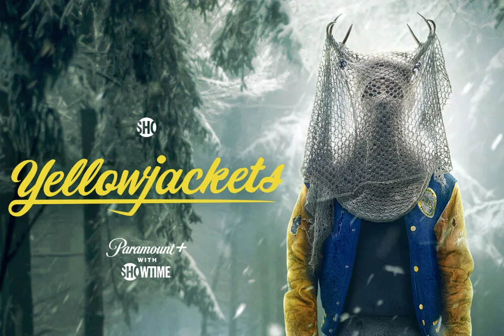 Key art for Yellowjackets Season 2 featuring a figure wearing a deer skull and a fishing net veil over a varsity jacket, against a snowy forest background.
