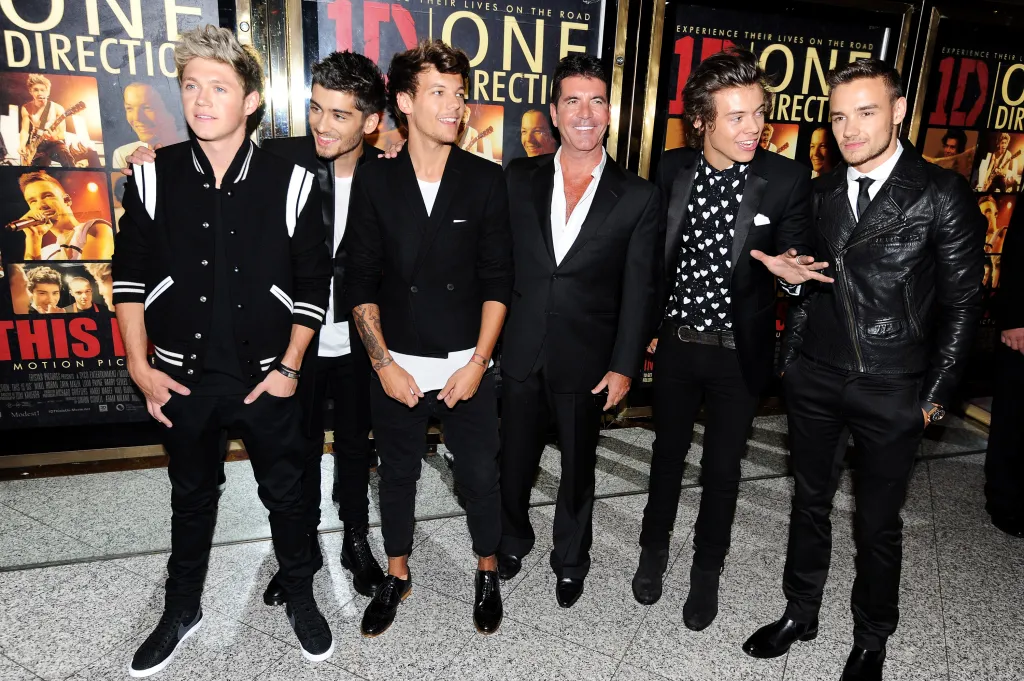 One Direction members Niall Horan, Zayn Malik, Louis Tomlinson, Harry Styles, and Liam Payne, standing with Simon Cowell, at the premiere of