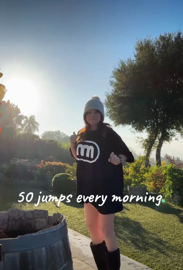 Valerie Bertinelli in a beanie and black t-shirt jumping outdoors, with text 