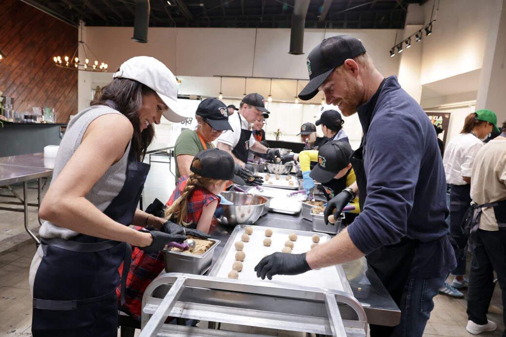 Meghan Markle and Prince Harry with their kids and others volunteering at Our Big Kitchen Los Angeles to bake cookies for community members.