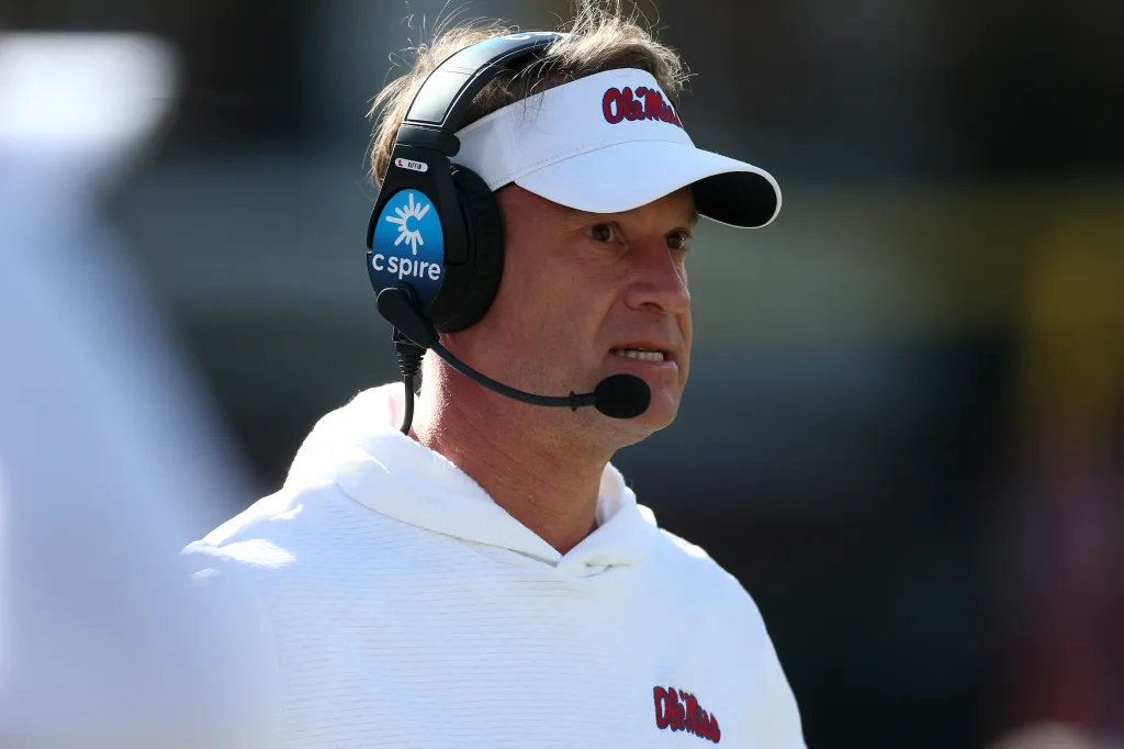 Mississippi Rebels head coach Lane Kiffin in a white visor and headset.