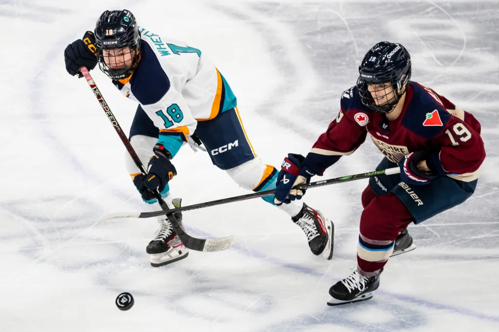 New York Sirens' Maddi Wheeler (18) and Montréal Victoire's Kaitlin Willoughby (19) vie for the puck in a hockey game.