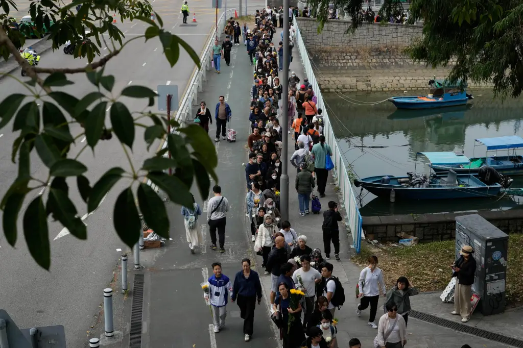 People line up to offer flowers and prayers for the victims of the deadly fire.
