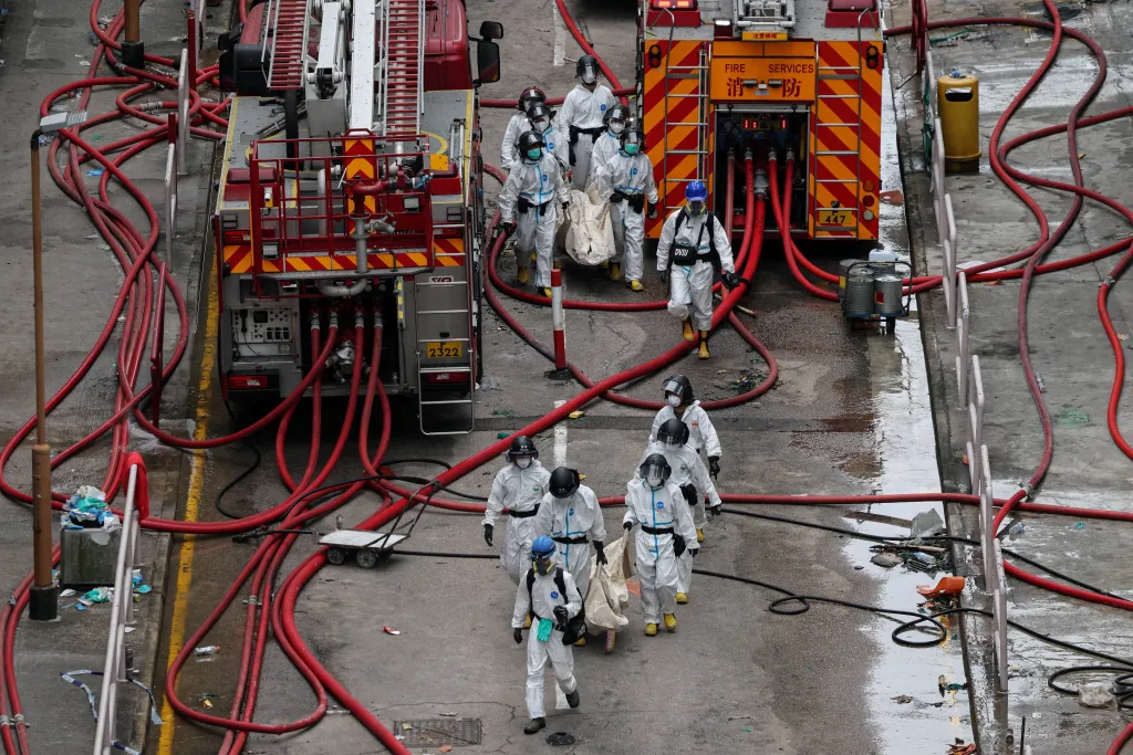 Firefighters carry bodies recovered from the fire-damaged residential buildings.