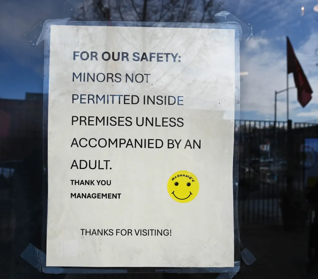 Sign on a McDonald's door stating minors are not permitted inside unless accompanied by an adult.