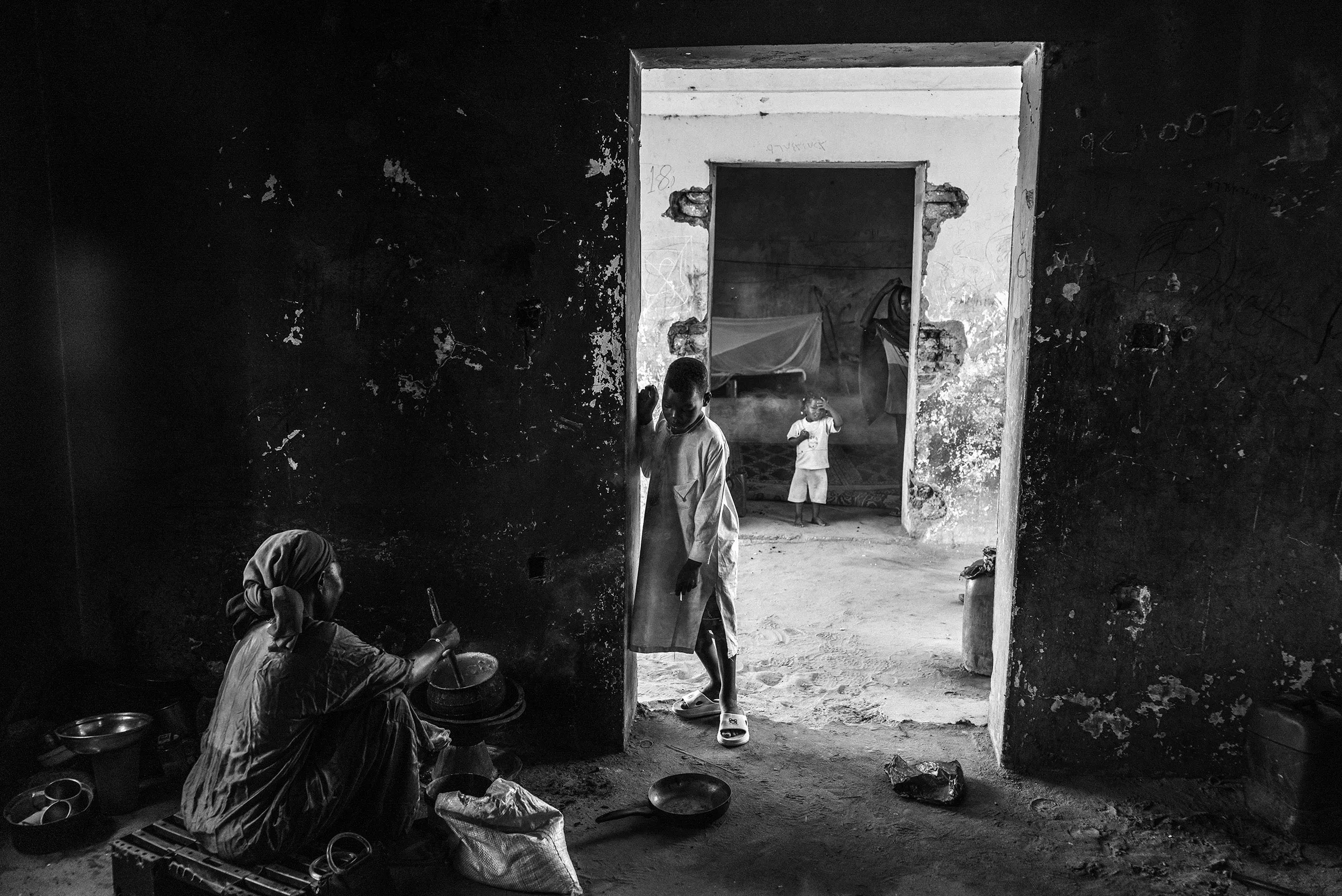 A woman cooks in the shadows of a former orphanage while children move through adjoining rooms, now converted into living quarters for families displaced from Khartoum. The abandoned compound on the outskirts of Al Junaynah shelters dozens who fled Sudan’s civil war.
Photograph by Moises Saman for TIME