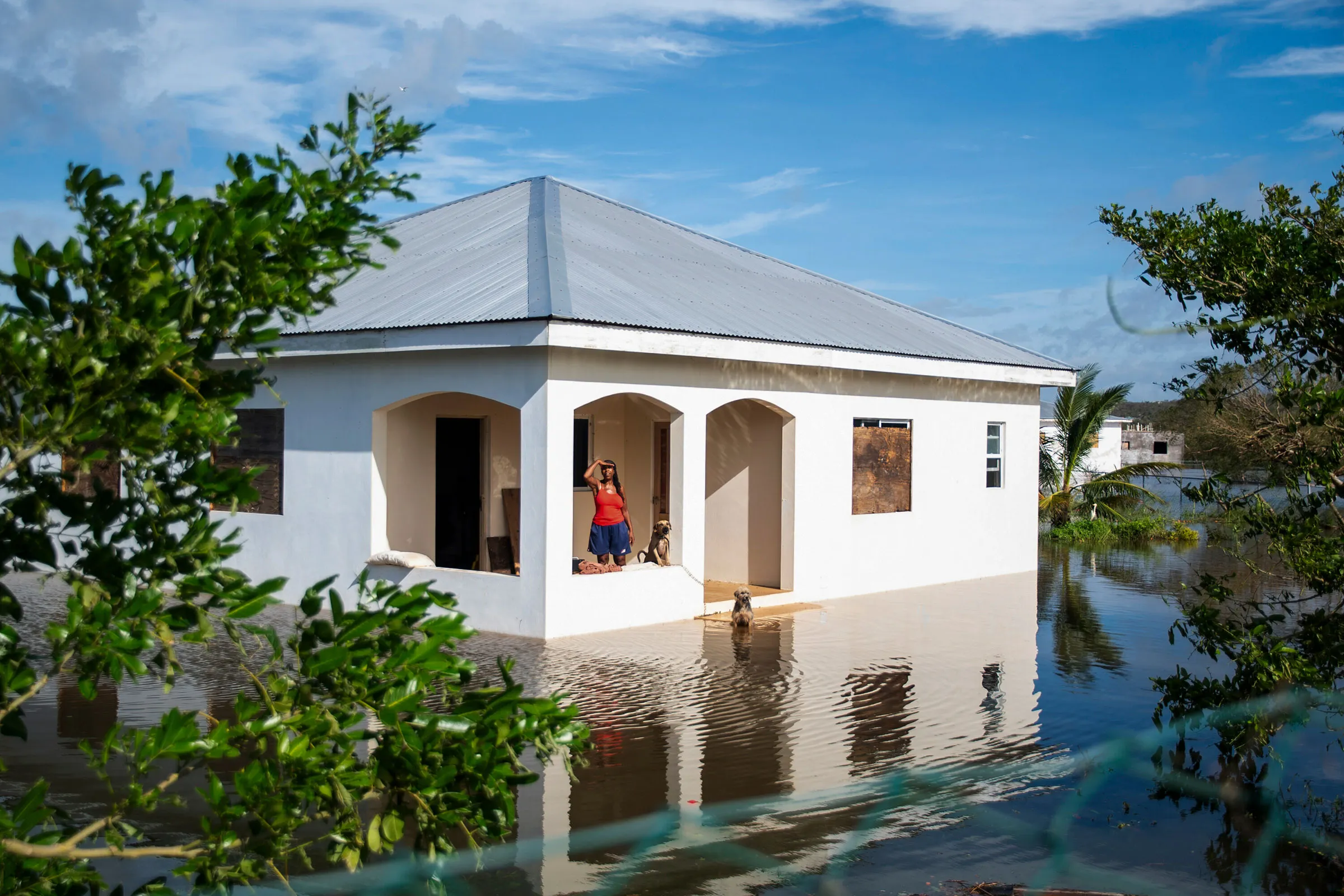 Lorraine Smith stands on her porch in Great Bay with her dogs amid flooding following Hurricane Melissa in the Treasure Beach area of Jamaica, on Wednesday, Oct. 29, 2025. (Abbie Townsend/The New York Times)