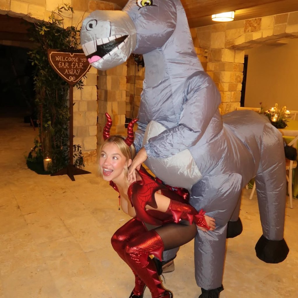Sydney Sweeney in a red dragon costume with horns, interacting with someone in an inflatable Donkey costume from Shrek.