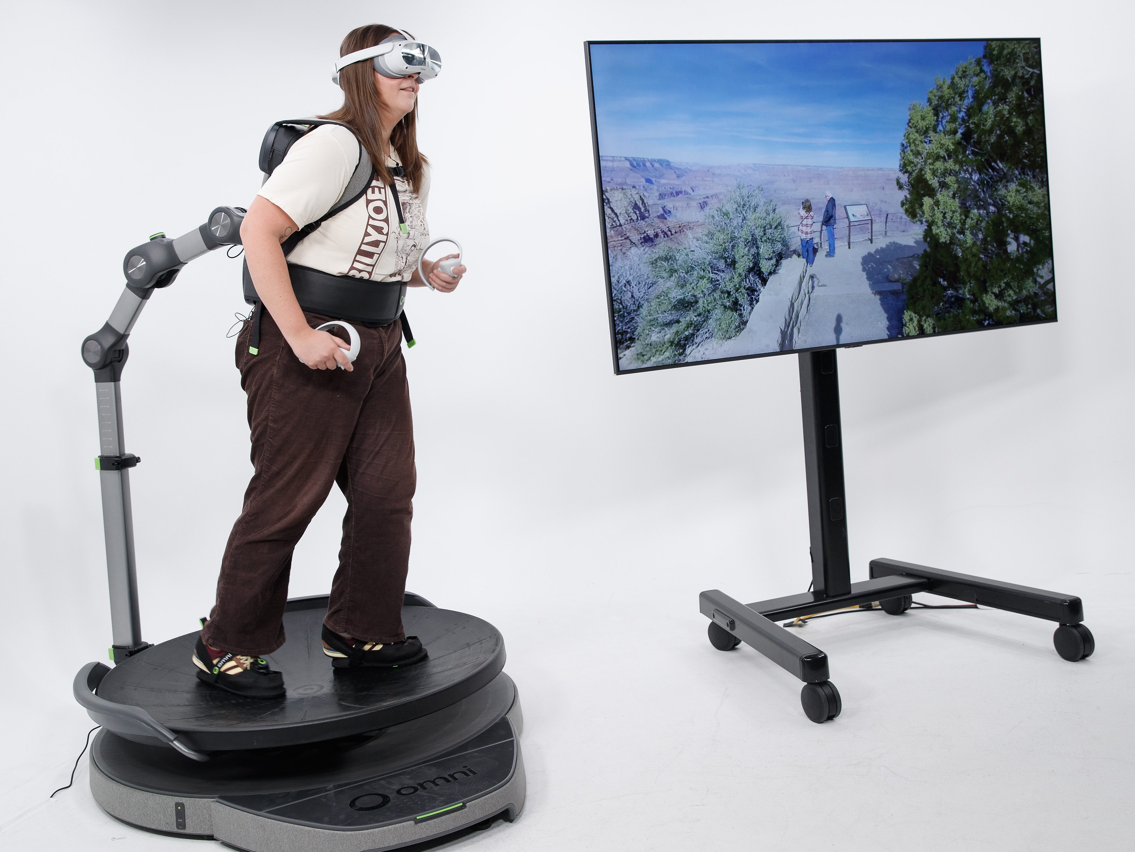 Wellness writer McKinzie Beard demonstrates the Omni One virtual reality system while a Grand Canyon scene is displayed on a monitor.