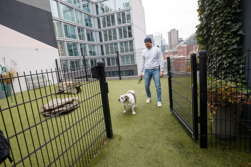 Chris DiStefano with his dog Ripley in a fenced-in dog run on the 8th floor of an apartment building.