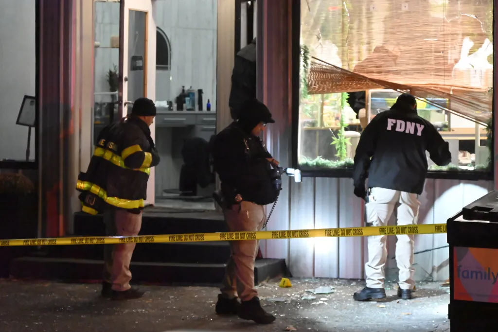 Police and FDNY investigating an arson at a barber shop in Manhattan, New York, with shattered windows and a yellow 