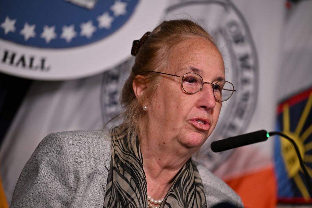 Woman in glasses speaking into a microphone.