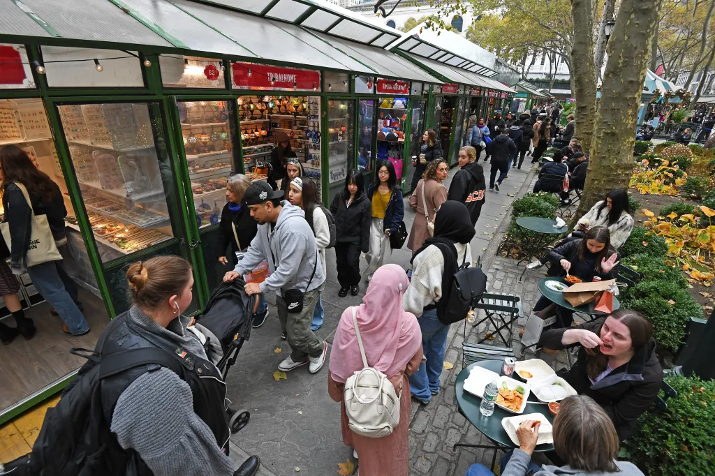 People shopping and eating at market stalls at Bryant Park, New York City.