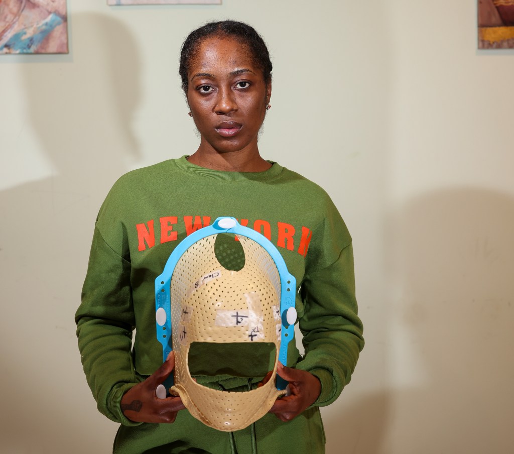 Elizabeth Fleurisma holding the lead mask she wore during radiation treatment for a brain tumor.