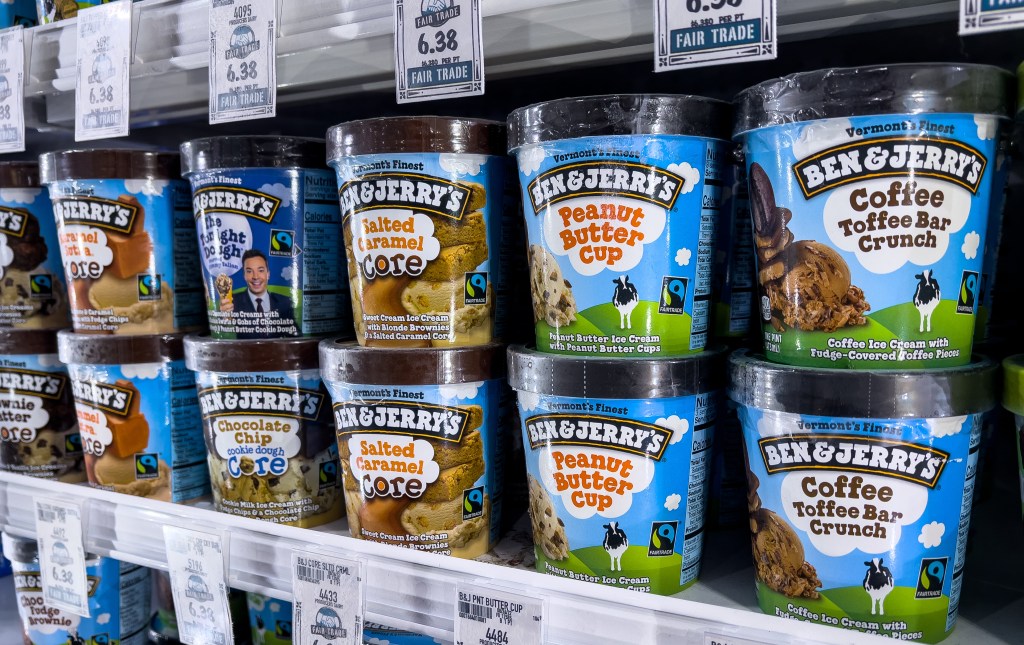 Ben & Jerry's ice cream containers in a supermarket freezer aisle.