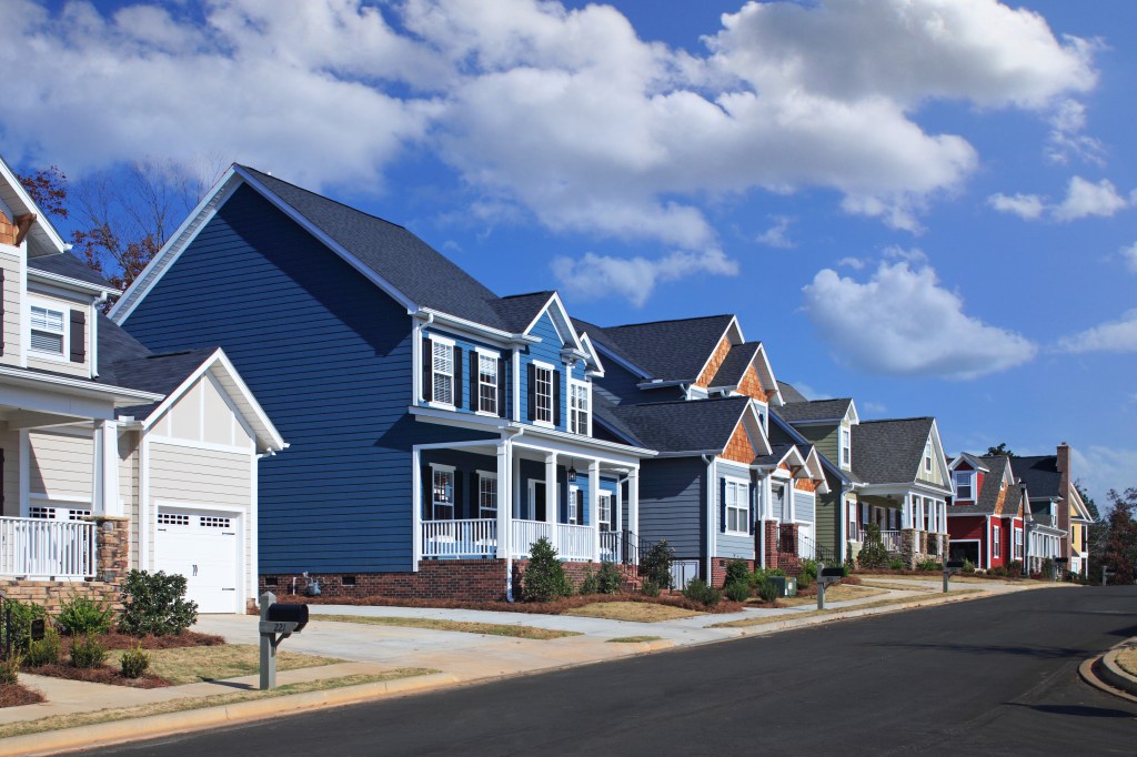 Row of blue, gray, and red suburban houses on a sunny day.