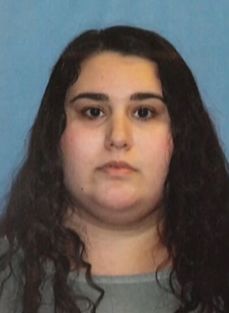 A woman with long dark curly hair and dark eyes looking forward.