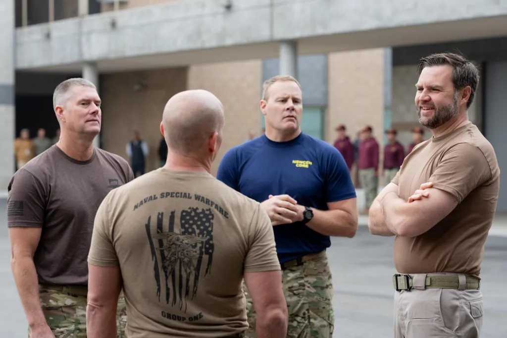 Four men, three of them in military attire, stand outside a building.