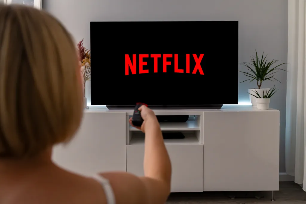 Woman watching Netflix on a TV with a remote control.