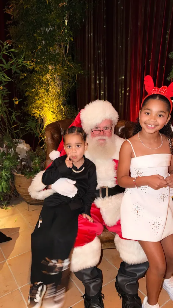 Santa Claus sitting with a young boy on his lap and a young girl standing next to him.
