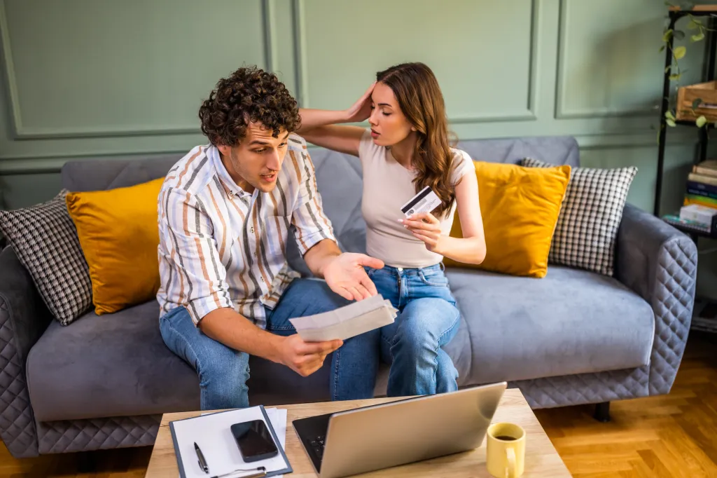 Couple arguing about home finances in the living room.