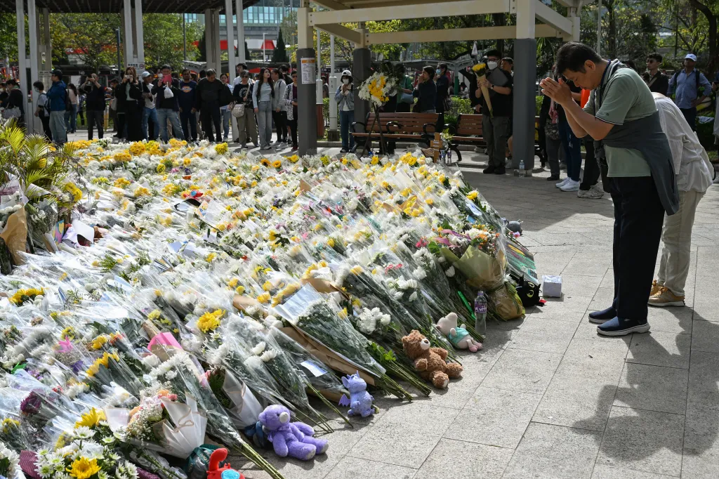 People laying flowers and stuffed animals outside the Wang Fuk Court apartment blocks after a deadly fire in Hong Kong's Tai Po district.