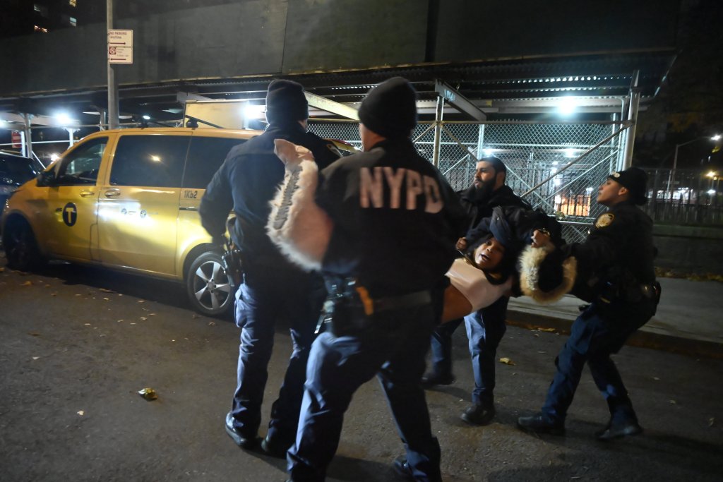 NYPD officers detaining a woman and placing her into a police cruiser in the Bronx.
