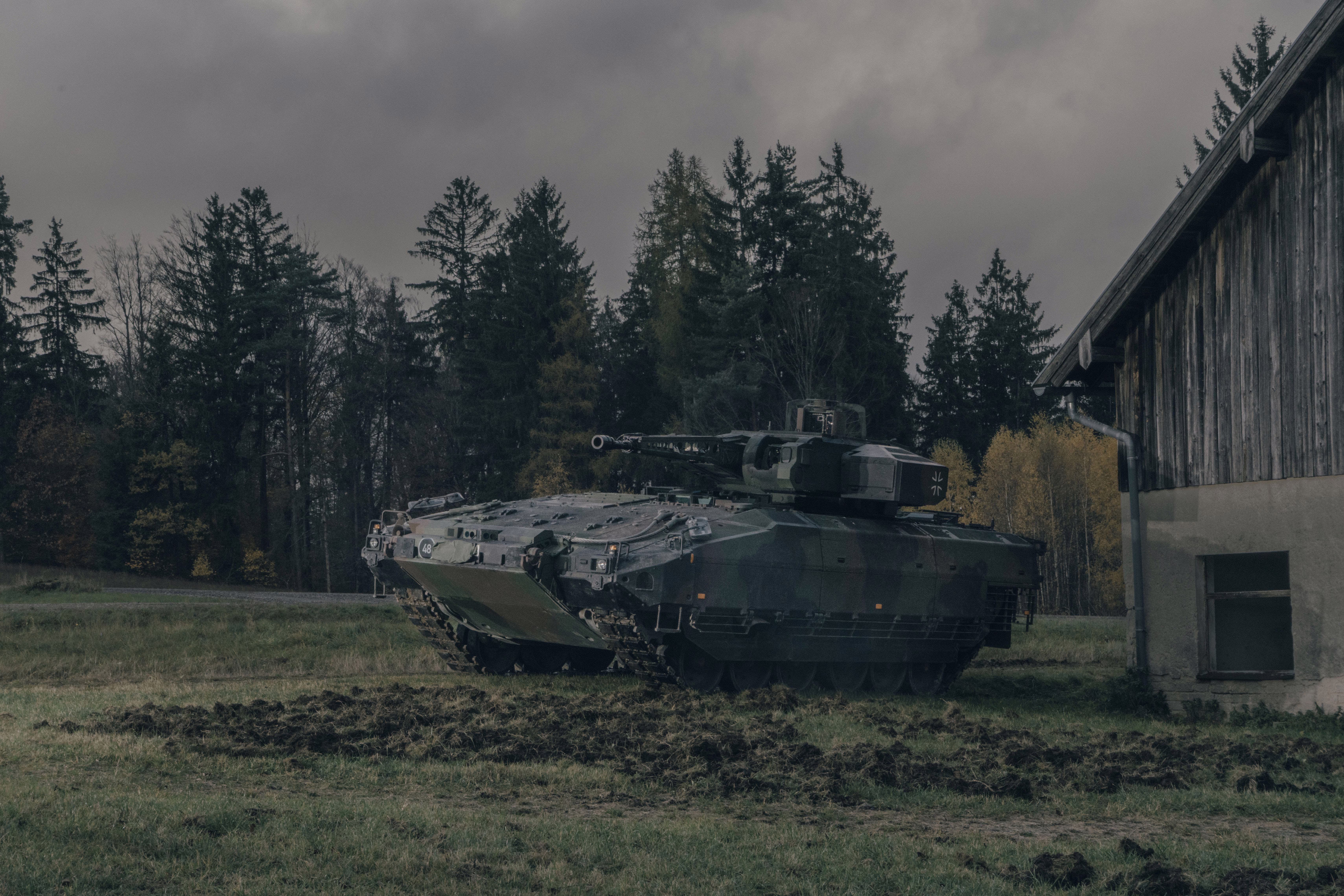 photo of tank next to wood-sided building with trees in background