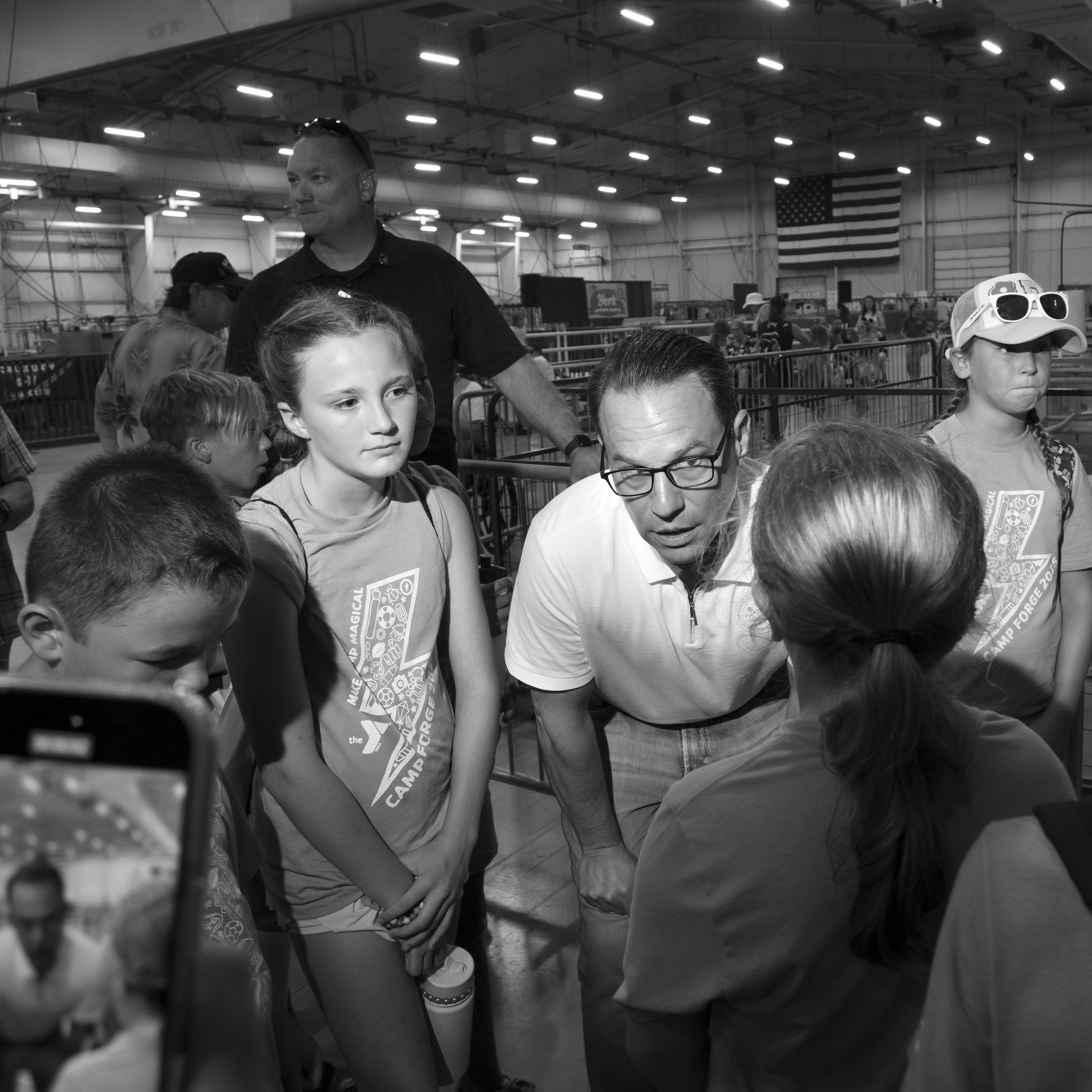 A black and white photograph of Josh Shapiro speaking to a group of young people at a day camp