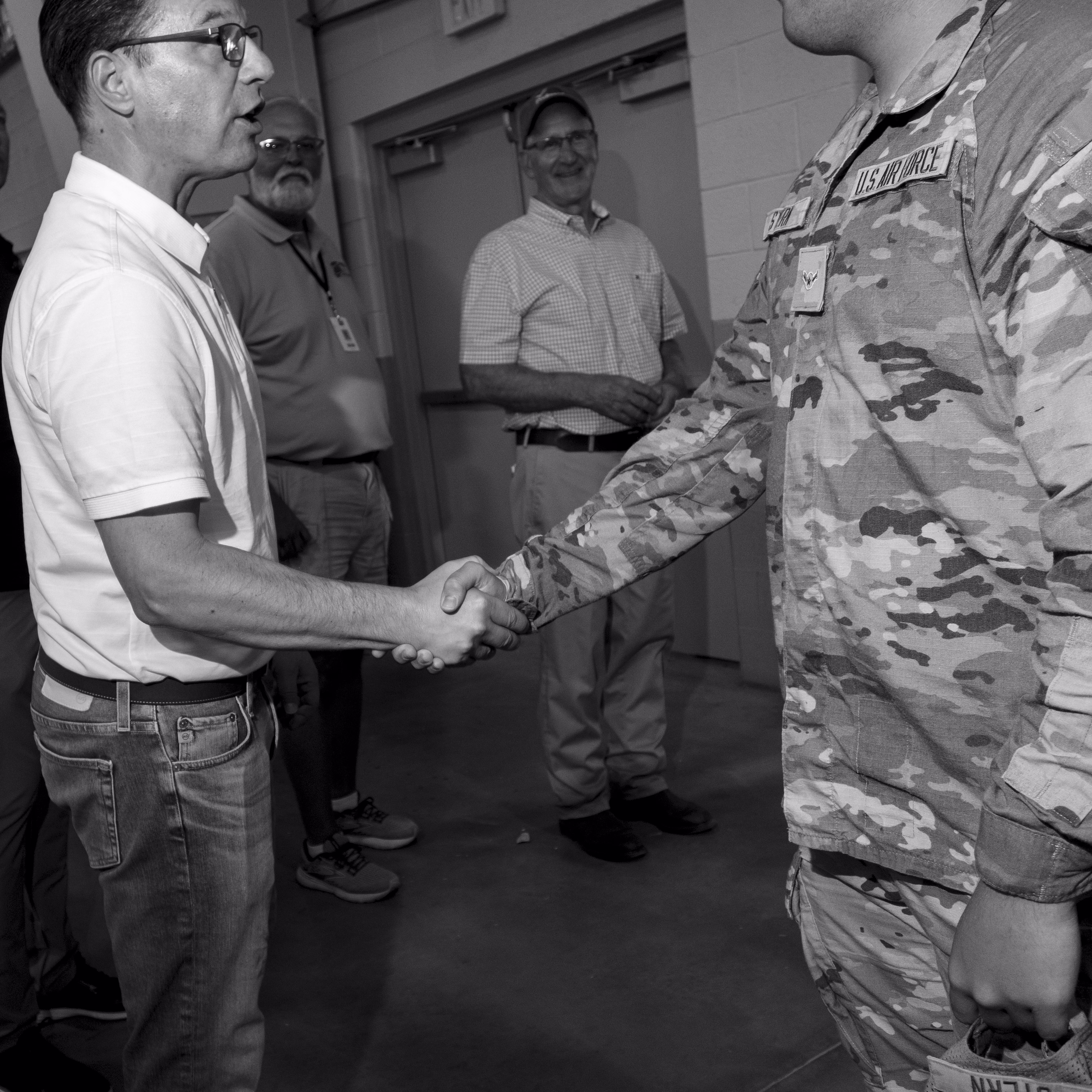 A black and white photograph of Josh Shapiro shaking hands with a man in US military fatigues