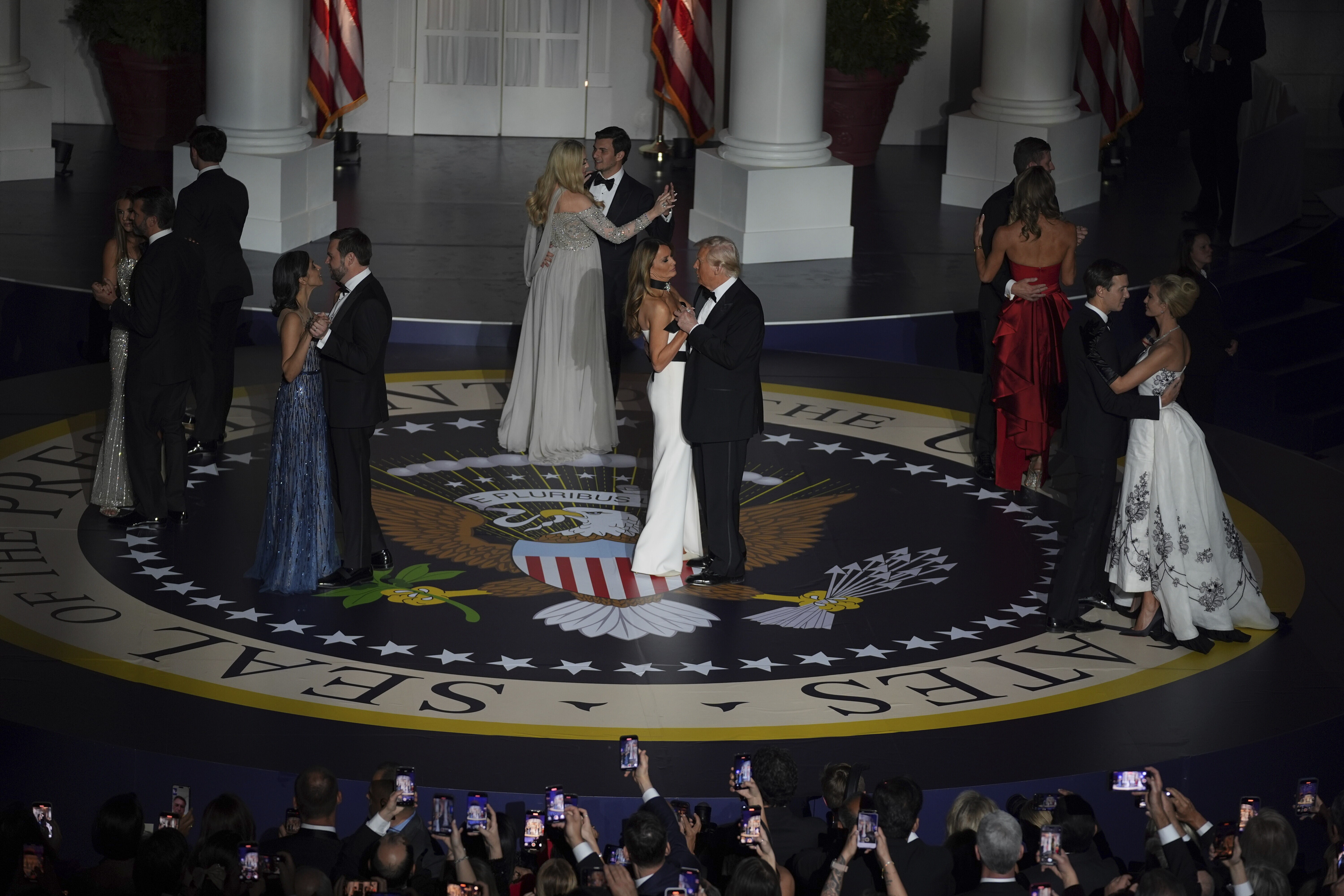 President Donald Trump, first lady Melania Trump, and others dance on a circular stage covered with the seal of the president of the United States.