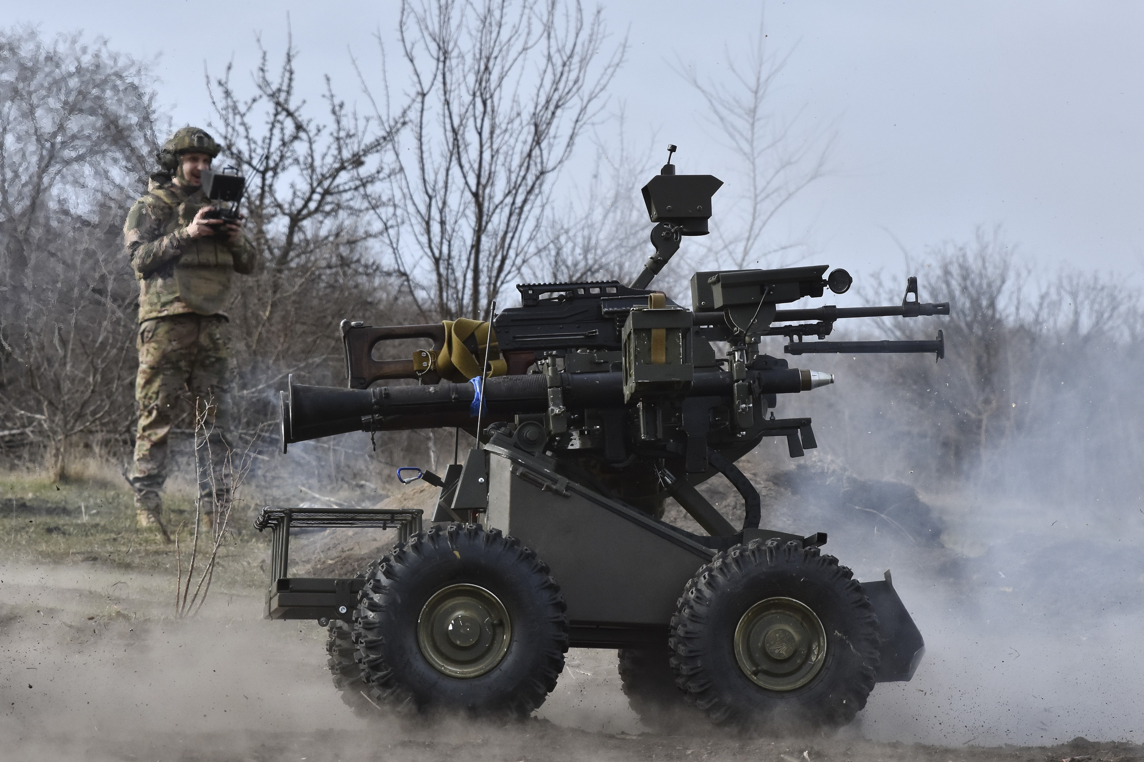 A soldier pilots a ground-based drone—a small four-wheeled vehicle mounted with several weapons.