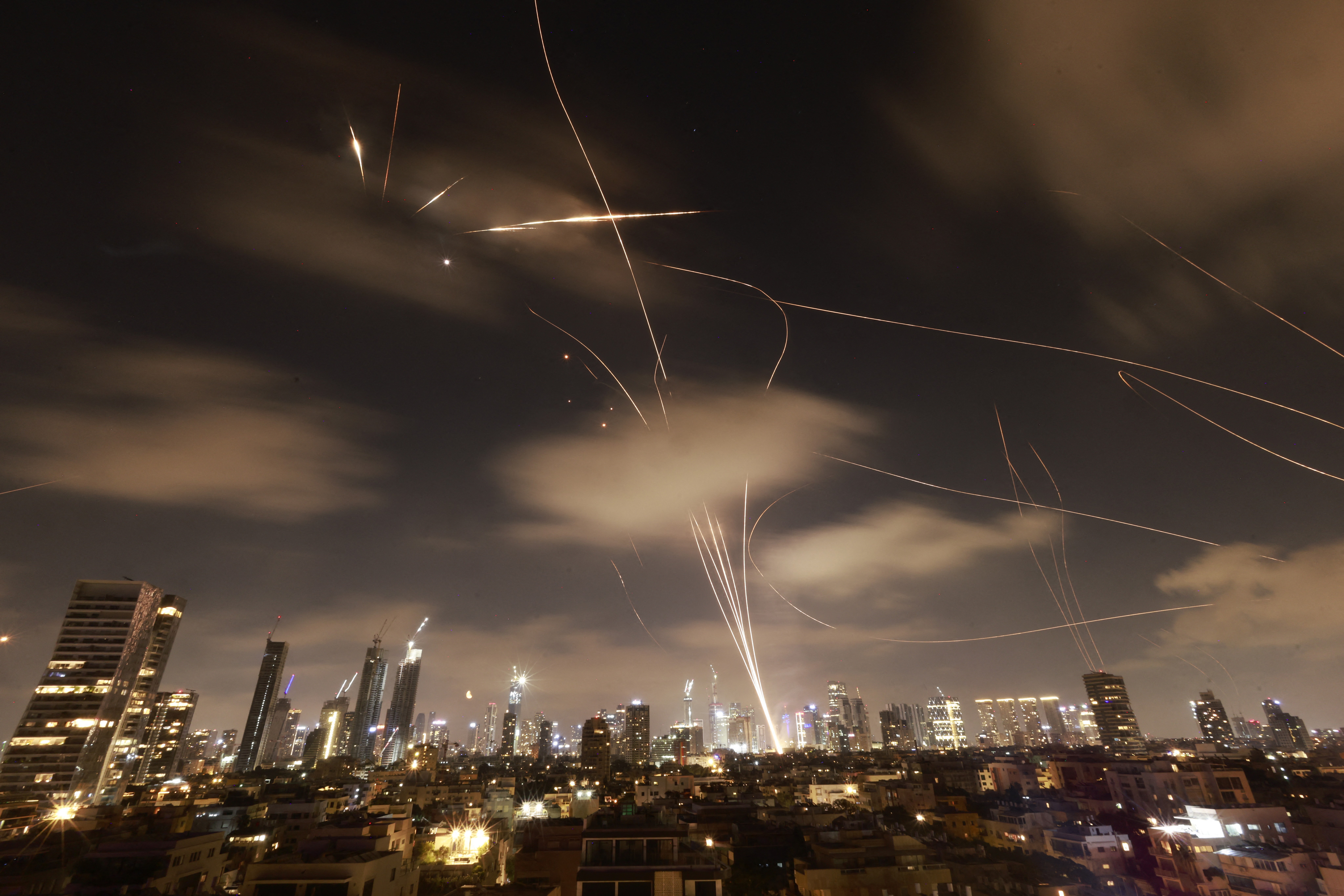 Incoming and outgoing missiles leave streaks of light in the sky above a city in Israel.