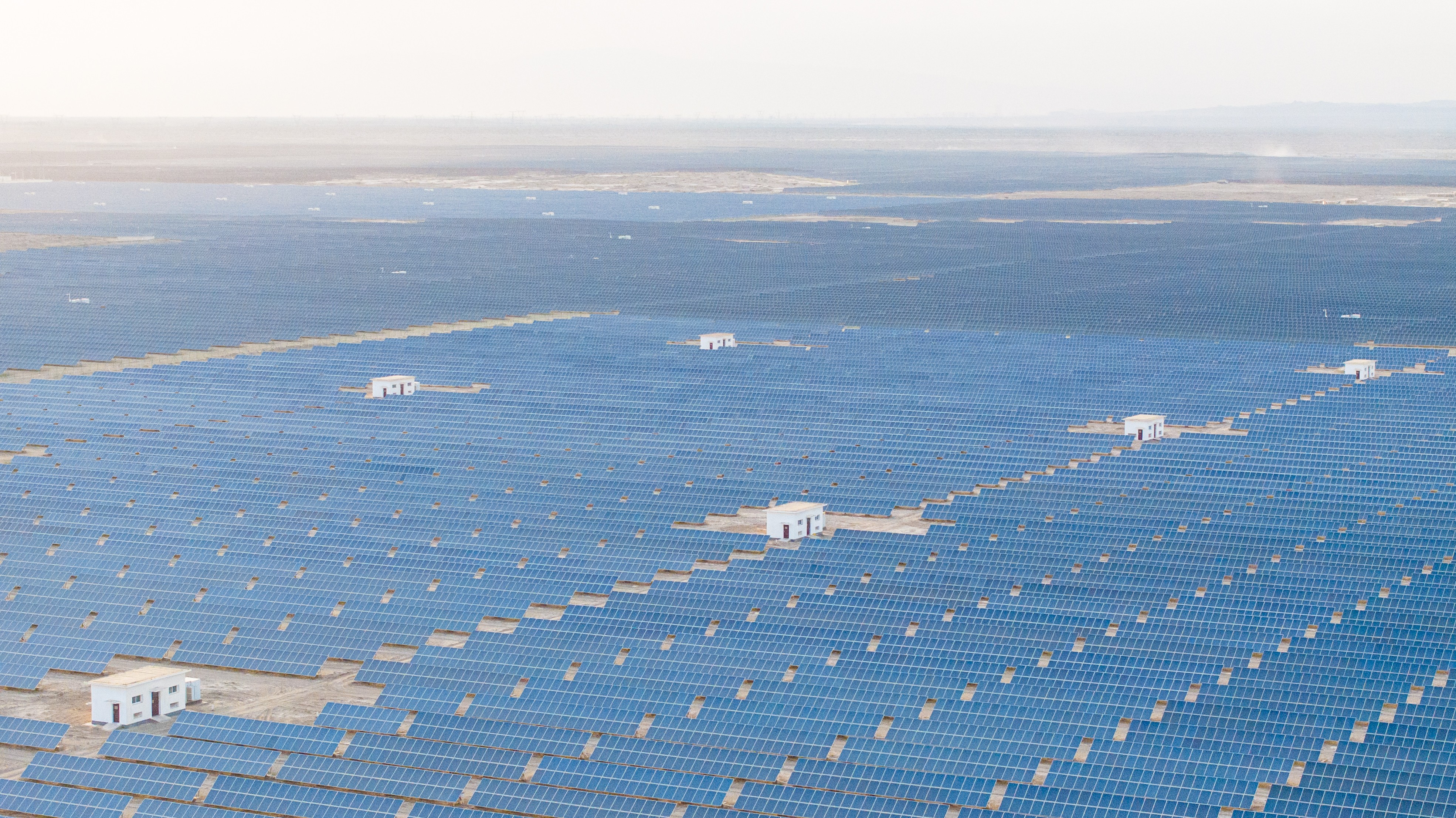 An aerial view—solar panel grids in a desert, stretching to the horizon