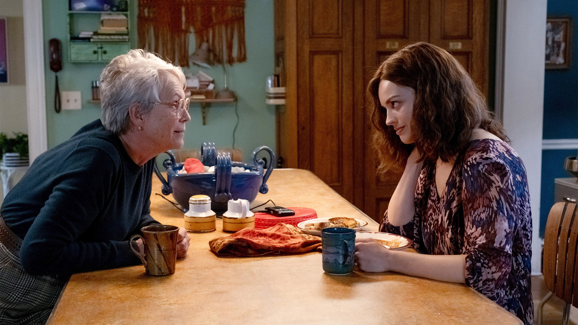 Emma Mackey and Jamie Lee Curtis sit at a dining table