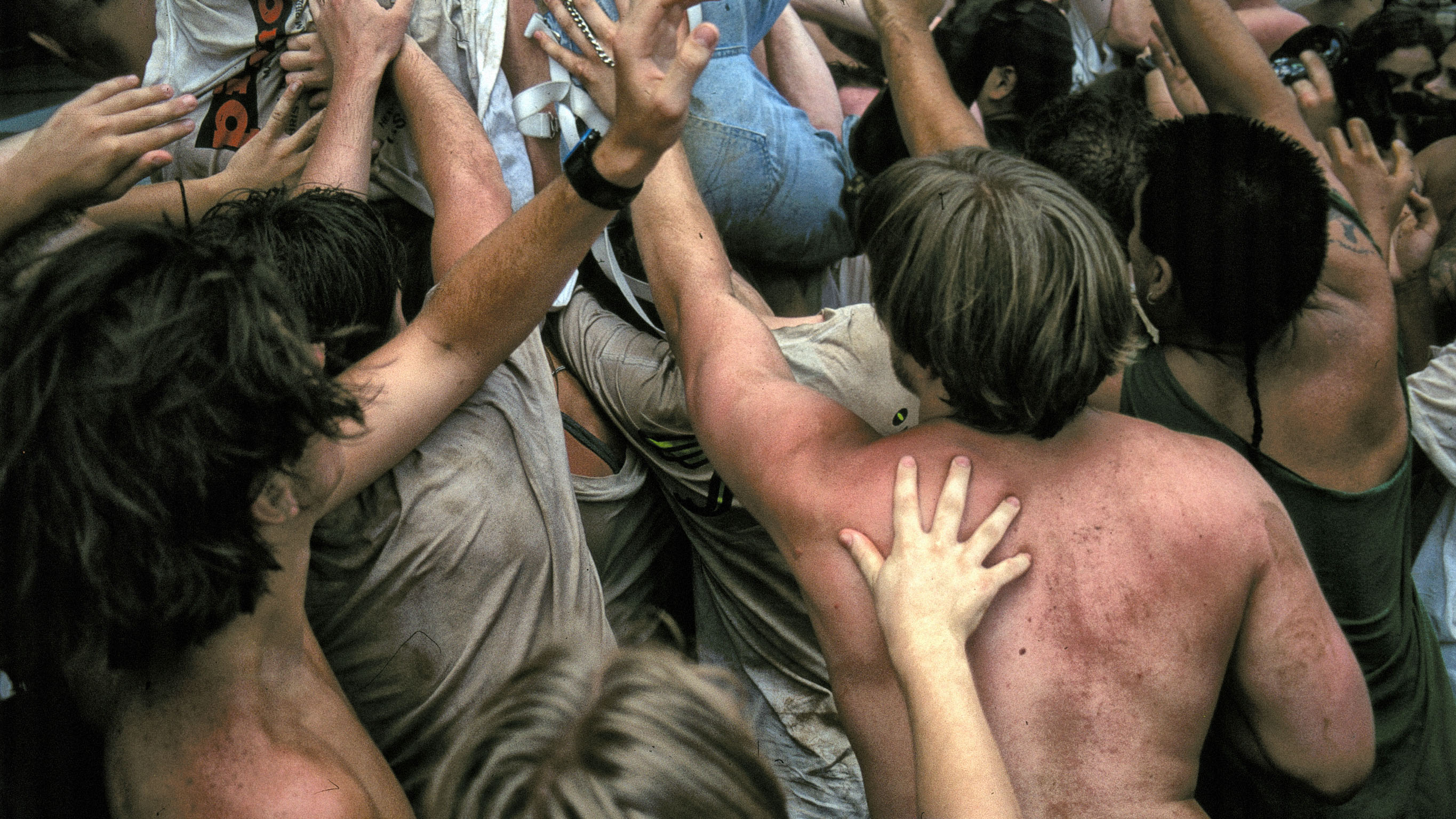 A color photograph of sweaty, dancing people in a moshpit