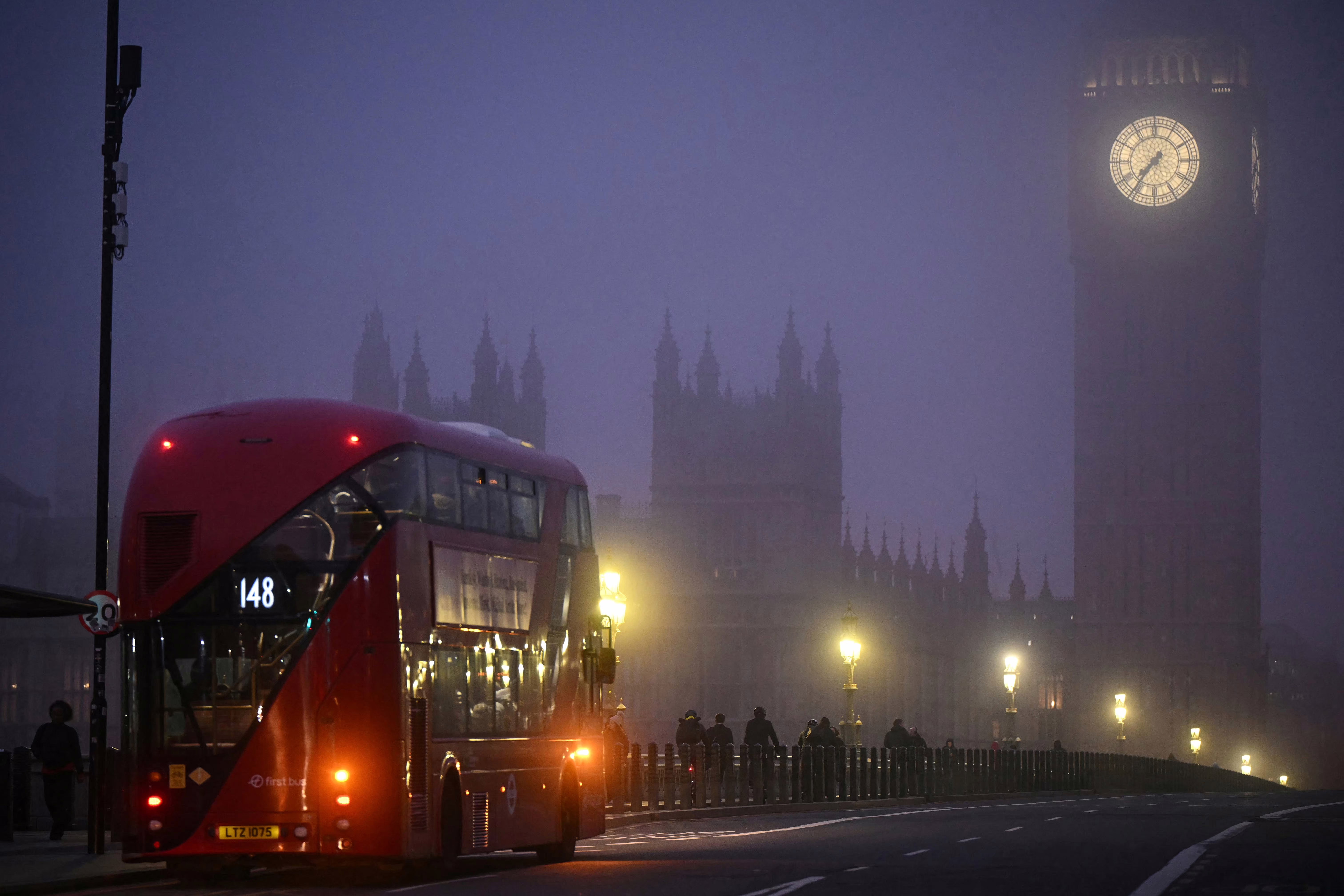 A double-decker bus crosses Westminster Bridge as fog covers the streets of London.