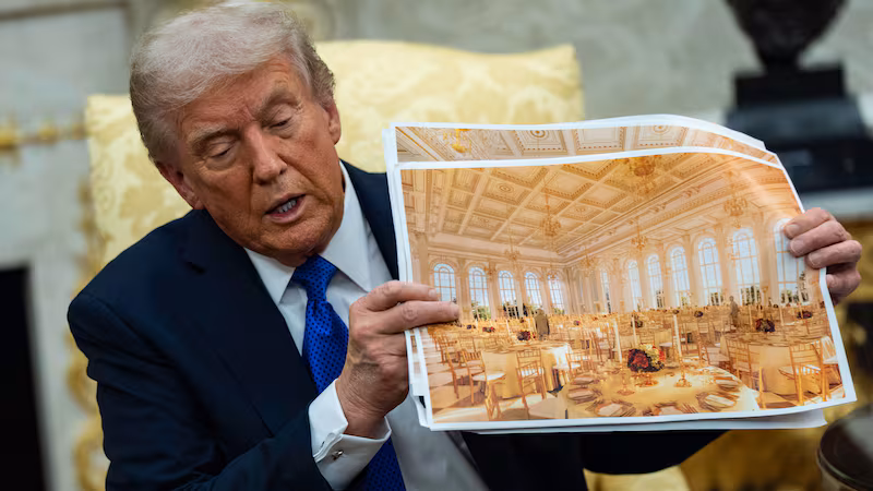 U.S. President Donald Trump speaks holding a photos of the new ballroom