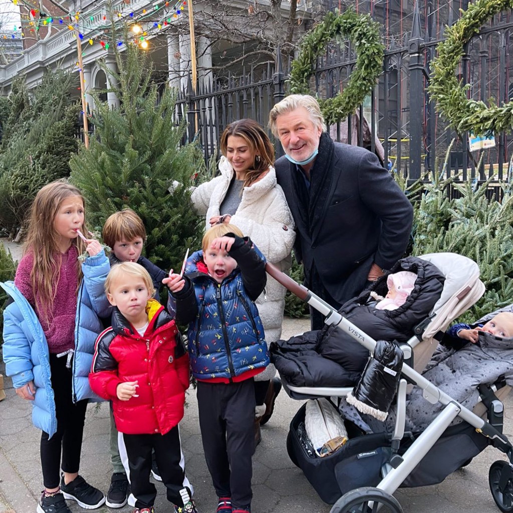 Alec and Hilaria Baldwin with their six children on a street decorated with Christmas trees and lights.