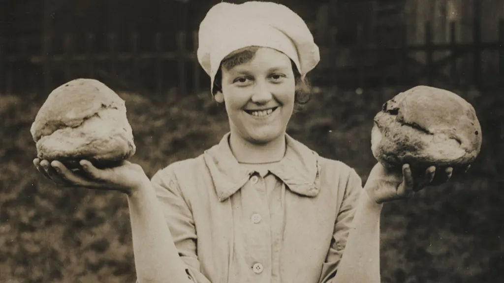 A member of the Women’s Army Auxiliary Corps proudly displaying two fresh loaves of bread.