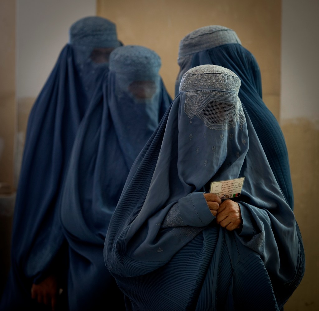 Afghan women in burqas waiting in line at a polling station in Kabul, Afghanistan.