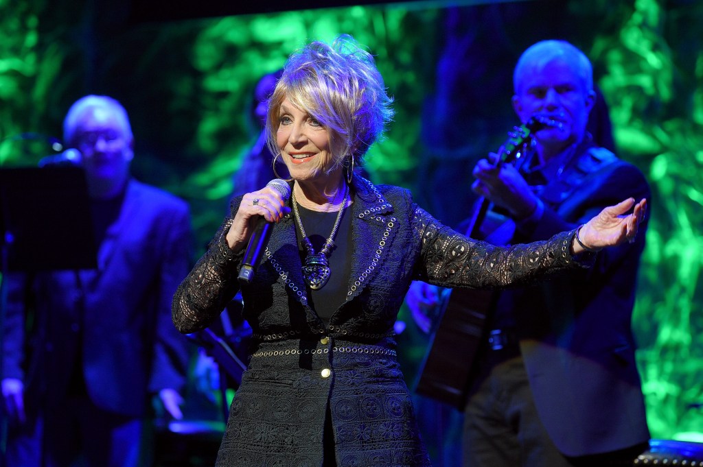 Jeannie Seely performs onstage, holding a microphone.