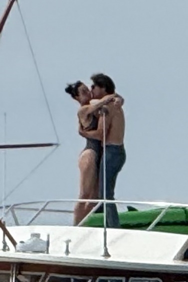 Katy Perry in a black swimsuit and Justin Trudeau shirtless kissing on a yacht.
