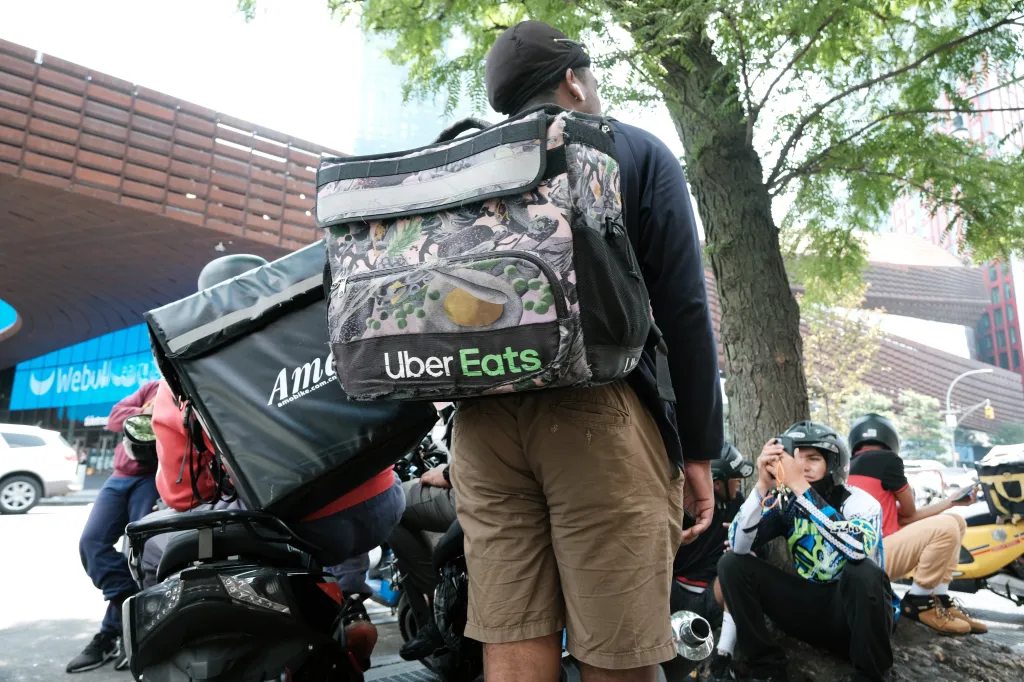 An Uber Eats delivery worker wearing a delivery backpack.