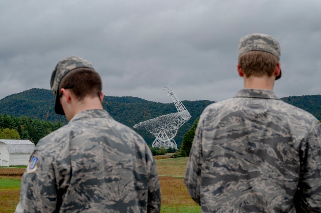 Two men in military fatigues looking at the Green Bank Telescope.